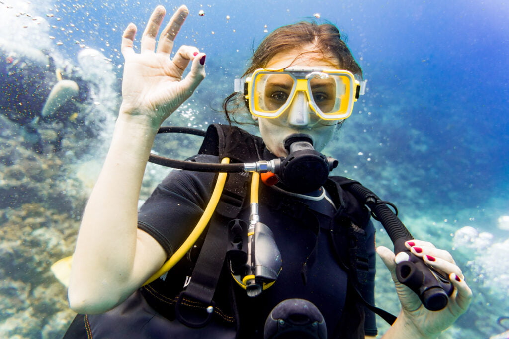 Woman diving on coral reef giving the ok sign